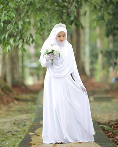 a woman in a white dress is walking down the street with flowers on her hand