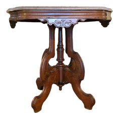 an antique wooden table with marble top and scrolled design on the base, isolated against a white background