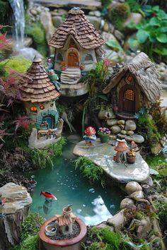 a miniature garden with lots of small houses and water features in the pond, surrounded by rocks