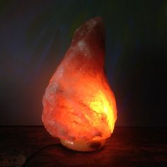 a large rock lamp sitting on top of a wooden table next to a dark wall