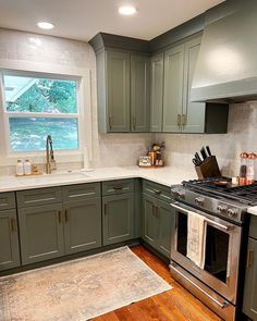 a kitchen with green cabinets and stainless steel stove top oven in the middle of it