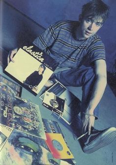 a young man sitting on top of a skateboard in front of various posters and cds