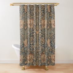 a shower curtain with a blue and beige floral design on it, hanging from a gold rod