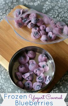 frozen yogurt covered blueberries in a bowl on a cutting board with text overlay