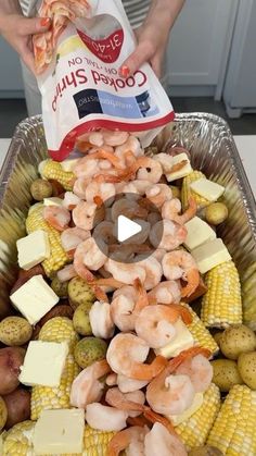 a person is holding a bag of shrimp and corn on the cob with cheese