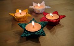 three crocheted stars are sitting next to two lit candles