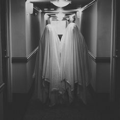 two white robes hanging from the ceiling in a hallway