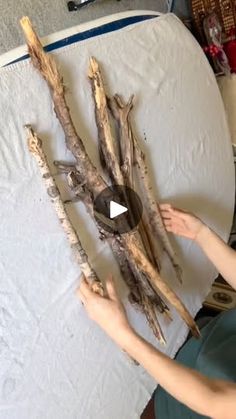 a person is making something out of driftwood and paper towels on a table top