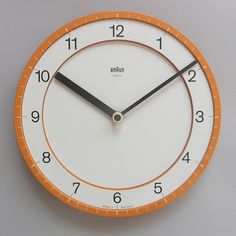 an orange and white clock with black hands