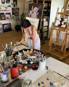 a woman painting in an art studio with lots of easels and paintbrushes