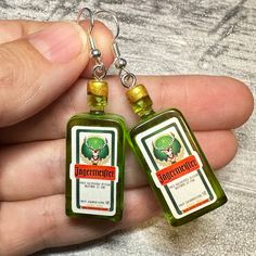 two green bottles are being held together by someone's hand and the bottle is hanging from them