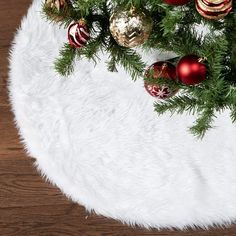 a christmas tree with red and gold ornaments on it's branches in front of a white rug