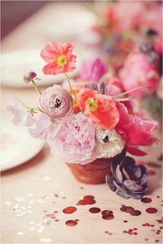 pink and red flowers in a vase on a table with confetti sprinkles