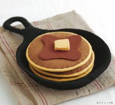 three pancakes in a skillet with butter on the top and syrup on the bottom