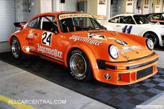 an orange race car parked in a garage