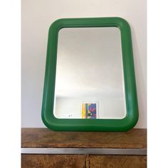 a green mirror sitting on top of a wooden dresser