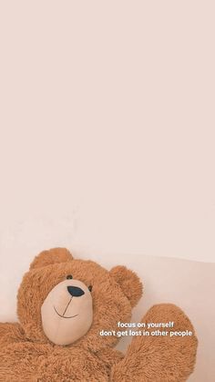 a brown teddy bear sitting on top of a white couch next to a wall with the words focus on yourself don't get in other people