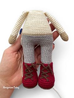 a crocheted stuffed animal with red shoes on it's feet is being held by a hand