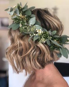 a woman with blonde hair wearing a flower crown on her head and greenery in her hair