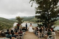 a couple getting married at the top of a hill with their wedding party in chairs