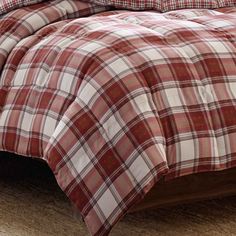 a red and white plaid comforter set on a bed with pillows in the background