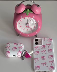 an alarm clock, cell phone case and keychain on a white table top