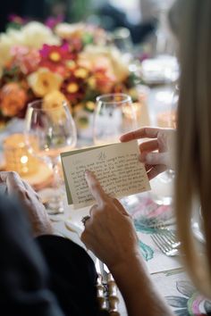 a woman is holding up a card at a dinner table