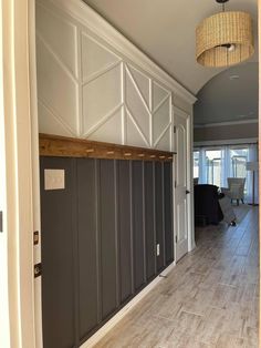 an empty hallway leading to a living room with gray walls and white paneled doors