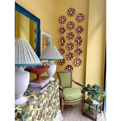 a living room with yellow walls and green chairs in front of a table topped with lamps