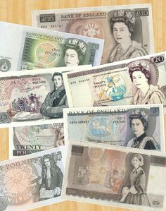 five different british bank notes sitting on top of a wooden table next to each other