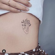 a woman's stomach with a flower tattoo on her lower back and the side