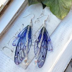 Our very pretty purple faerie wing earrings which are just perfect for any faerie! We make the wings ourselves and they are made from a type of plastic and magic, oh and a sprinkle of glitter of course! The two wings are separate which help create movement Finished with the best quality crystals and a pretty crystal drop, which catches the light perfectly! We make the wings ourselves and they are made from a type of plastic and magic, oh and a sprinkle of glitter of course! The two wings are separate which help create movement. We offer these earrings in sliver plated and bronze plated nickel free earring hooks Please note that no faeries have been harmed in the making of these wings! Villainous Outfits, Purple Fairycore Jewelry For Party, Vibey Jewelry, Knight Cookie, Tvd Dr, Wing Jewelry, Fairy Jewelry, Magical Jewelry, Pretty Purple