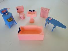 there are many toy furniture on the table and one has a sink, toilet, and chair