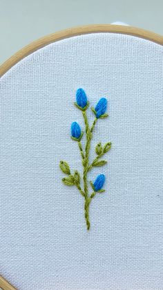 a close up of a embroidery on a piece of cloth with blue flowers in it