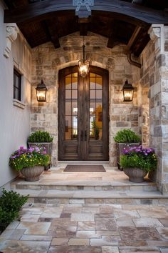 two planters with flowers are on the front steps of a house that is lit up