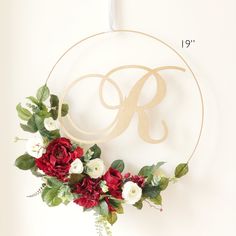 a floral wreath with the letter r hanging from it's side on a wall