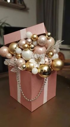 a pink box with gold and white ornaments in it sitting on top of a table