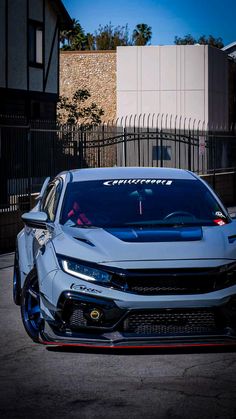 a silver car parked in front of a fence