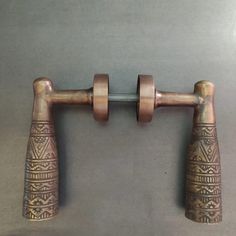 two metal handles with designs on them are hanging from a rod that is attached to the wall