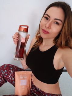 a woman sitting on the floor holding up a water bottle