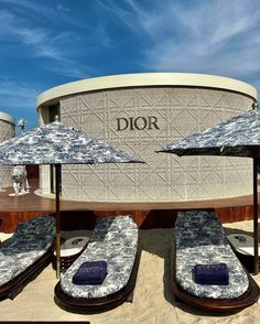 several lounge chairs and umbrellas in front of a dior store on the beach