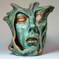 a green ceramic vase with a face on it's side and an open mouth