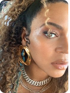 a close up of a person with curly hair and large hoop earrings on her head