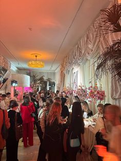 a large group of people standing in a room with white walls and drapes on the ceiling