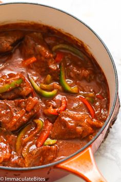 a pot filled with meat and peppers on top of a table