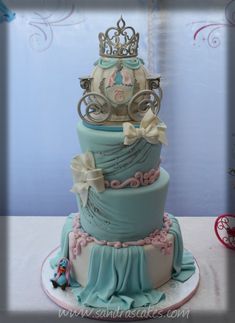 a three tiered cake decorated with princess carriage and tiara on it's top