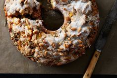 a bundt cake covered in nuts and powdered sugar with a knife next to it