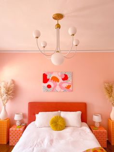 a bedroom with pink walls, white bedding and orange accents on the headboard