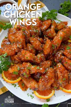 orange chicken wings on a white plate with garnish