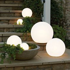 three white lights are on the steps next to a bowl with plants in front of it